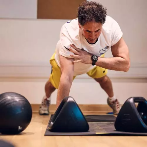 Fitness instructor doing a press up in front of kettle bells