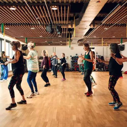 A group of people taking part in a Zumba dance exercise class in the gym