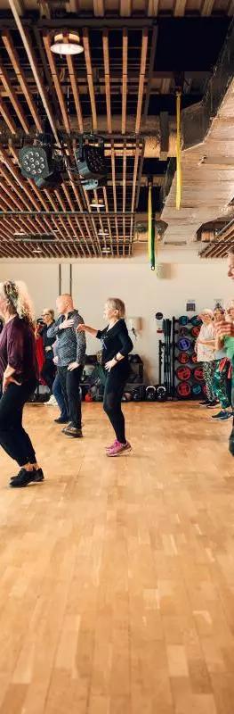 A group of people taking part in a Zumba dance exercise class in the gym