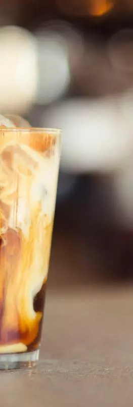An iced coffee in glass on a blurred table